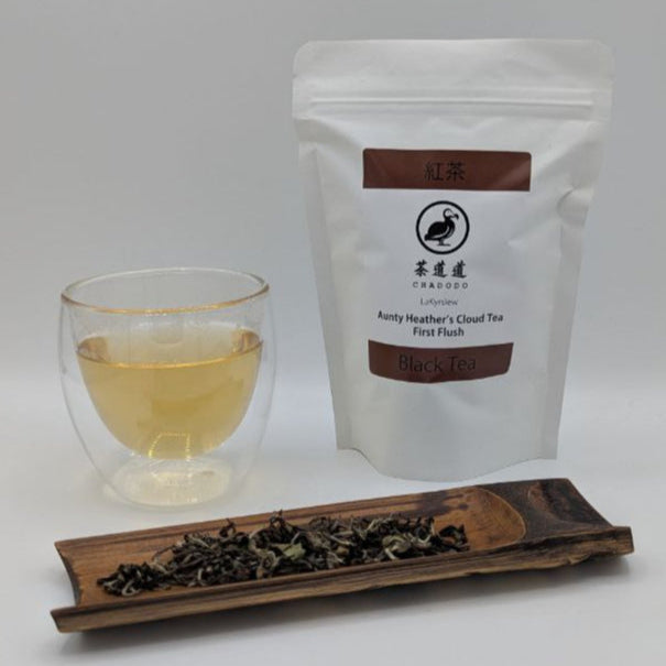 Aunty Heather's Cloud Tea First Flush packaging with a glass of tea and a bamboo tea scoop with loose-leaf tea on it